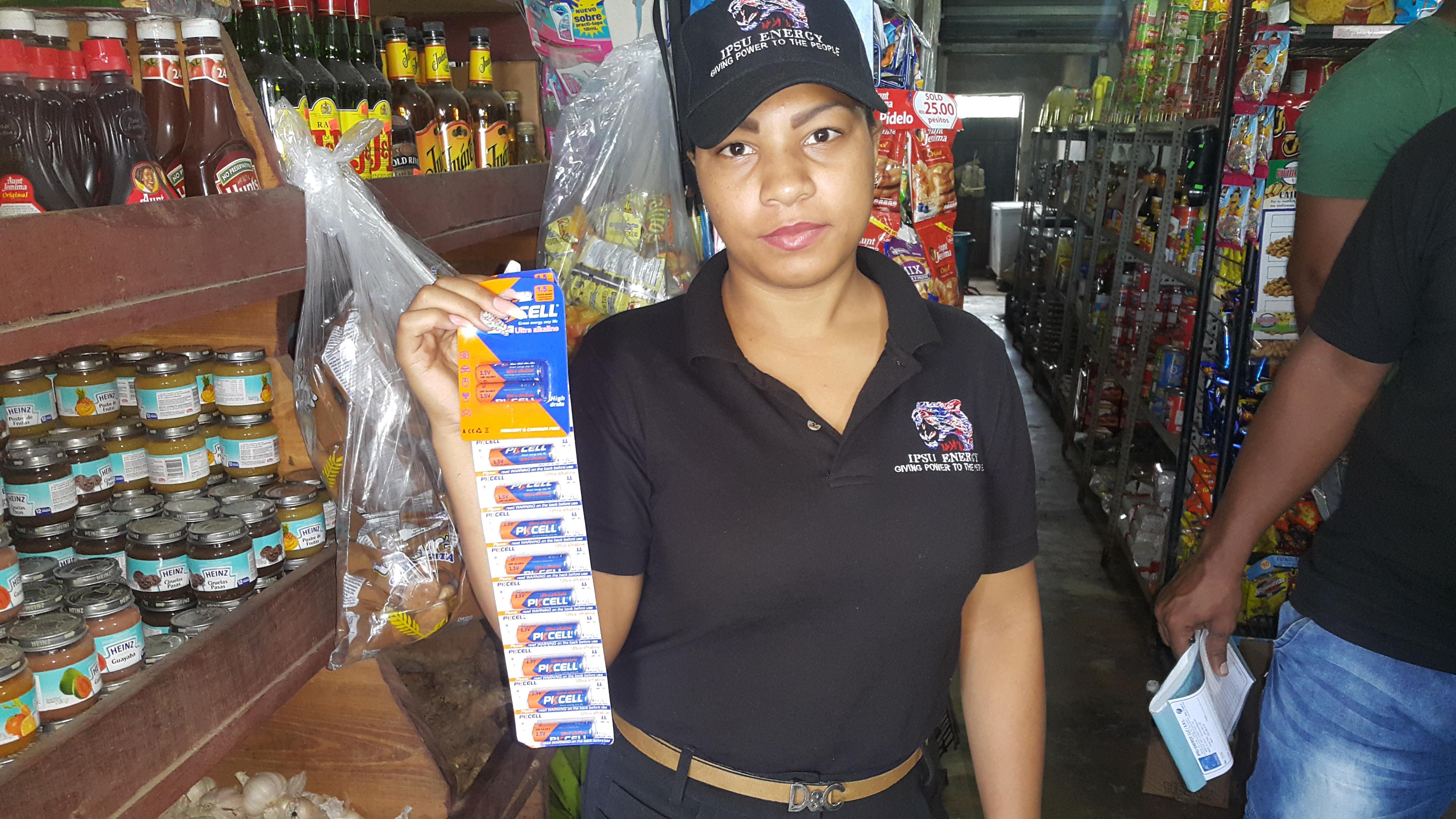 IPSU Energy representative holding PKCELL Ultra Alkaline battery strip in colmado store