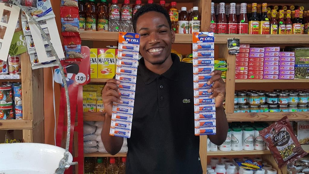 Colmado staff member holding PKCELL Ultra Alkaline battery packs